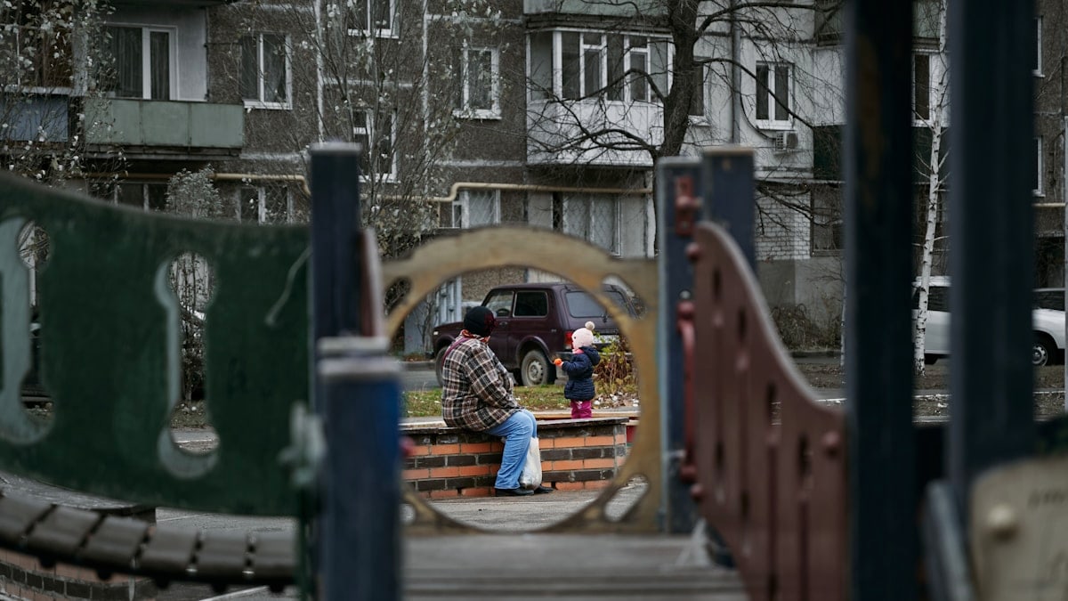 a man sitting on a wooden bench in a park